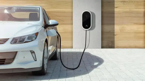 Biały samochód elektryczny podłączony do ładowarki ściennej. Czysta energia dla przyszłości.