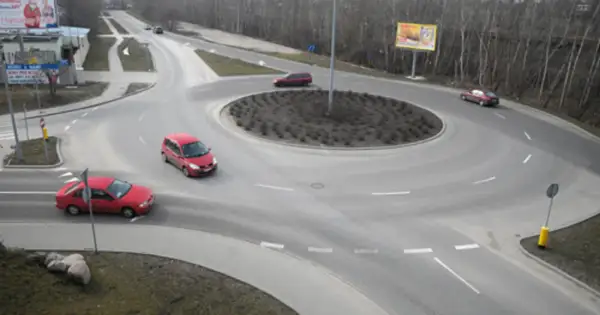 Rondo turbinowe jak jeździć? Czerwone samochody poruszają się po wielopasmowym rondzie, pokazując płynność ruchu.