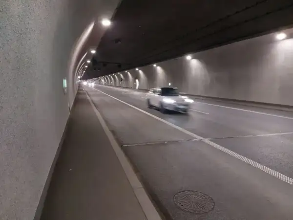 Biały samochód mknie przez oświetlony tunel zakopianka.