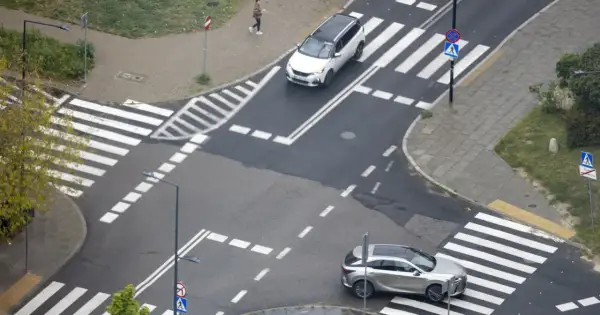 Na skrzyżowaniu równorzędnym dwa samochody zbliżają się do pasów.