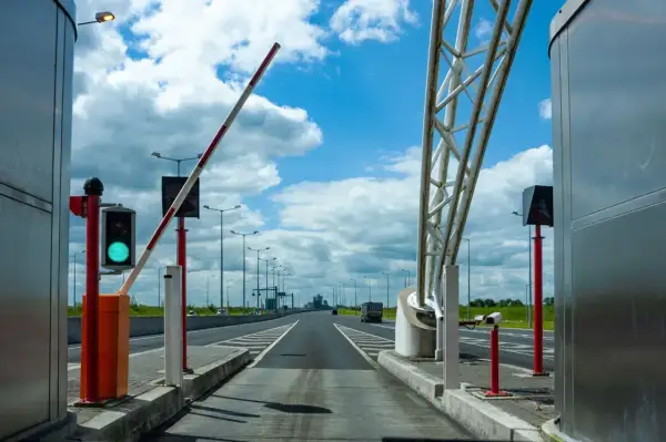 Brama na autostradzie A4 otwarta, zielone światło. Droga prowadzi w dal pod błękitnym niebem z chmurami.